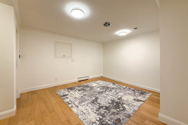 Bright, empty living room with hardwood floors and a large rug - 1249 Chartwell Place, West Vancouver