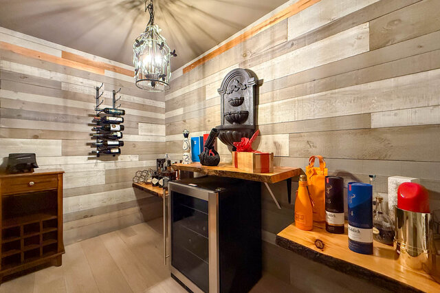 A bright interior lounge with a wine rack, mini fridge, and shelves holding bottles and containers - 1249 Chartwell Place, West Vancouver