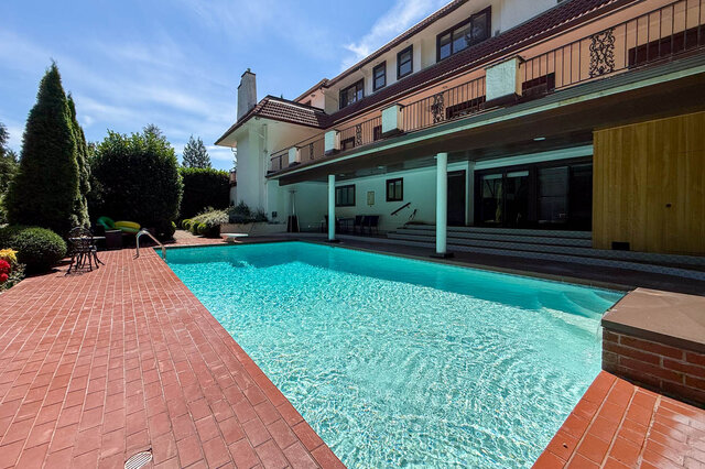 Exterior view of a house with a sparkling pool, large windows, and brick patio - 1249 Chartwell Place, West Vancouver