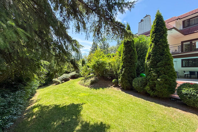 Sunny exterior view showcasing a landscaped garden with mature trees and a house with a balcony. - 1249 Chartwell Place, West Vancouver