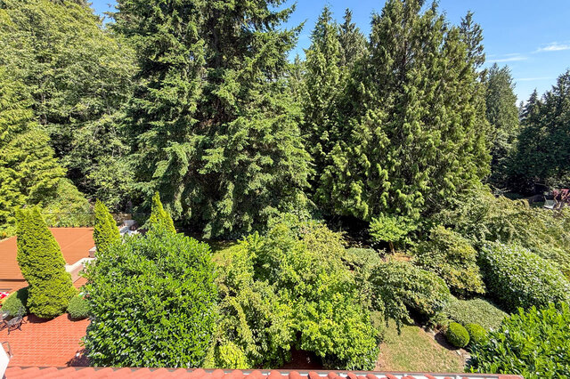 A scenic exterior view showcasing dense forest and mature trees surrounding a home with a red-tiled roof - 1249 Chartwell Place, West Vancouver