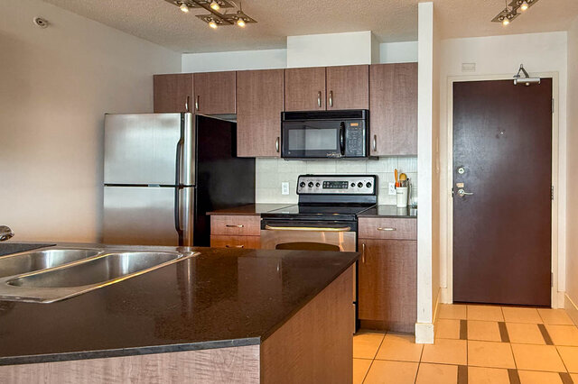 Bright kitchen with dark granite countertops and stainless steel sink. - 2113-610 Granville Street, Vancouver Downtown