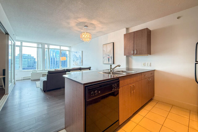 Bright kitchen with dark granite countertops and hardwood floors overlooking city skyline. - 2113-610 Granville Street, Vancouver Downtown