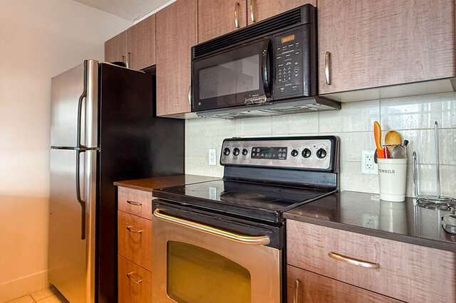 Bright kitchen with dark countertops and stainless steel appliances. - 2113-610 Granville Street, Vancouver Downtown