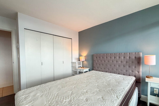 Furnished bedroom with tufted headboard and white sliding closet doors. - 2113-610 Granville Street, Vancouver Downtown
