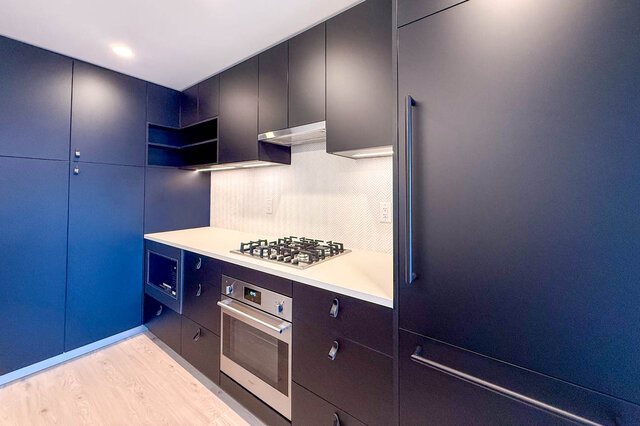 Bright kitchen with dark cabinetry, white countertops, and light hardwood flooring. - 204-1680 East 12th Avenue, Vancouver East Side