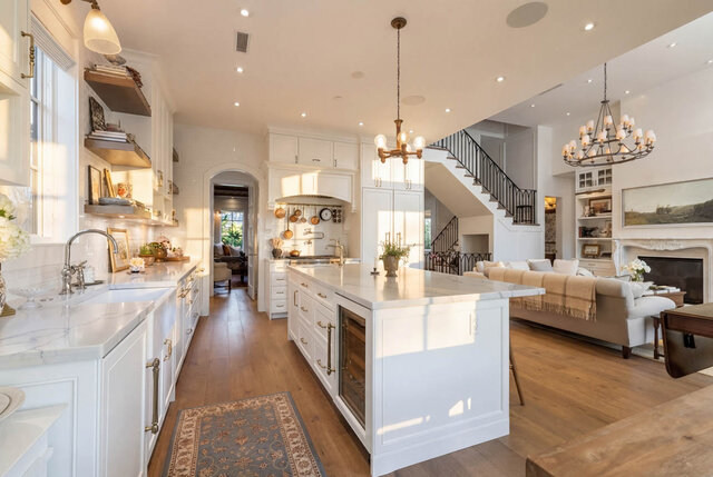 A bright kitchen with white cabinetry, hardwood floors, and a view into the living room with a fireplace - 1248 Kings Avenue, West Vancouver