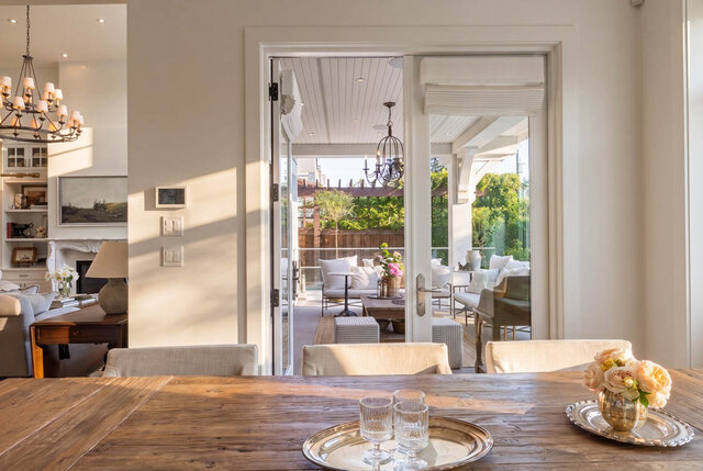 Dining area with wooden table, large sliding glass doors to patio, and view into living room - 1248 Kings Avenue, West Vancouver