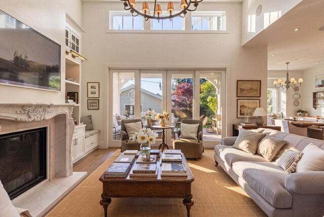 A bright living room with hardwood floors, a fireplace, and floor-to-ceiling windows overlooking a garden. - 1248 Kings Avenue, West Vancouver