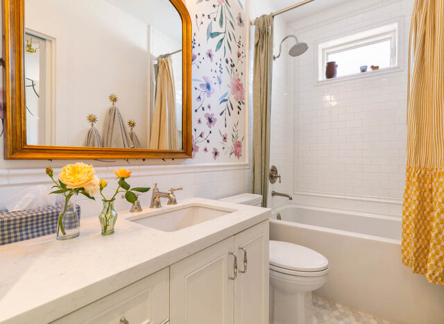 A bright bathroom with floral wallpaper, white tile walls, and a small window above the tub. - 1248 Kings Avenue, West Vancouver