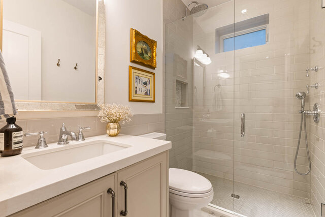 A bright bathroom with a glass shower, large mirror, and framed artwork. - 1248 Kings Avenue, West Vancouver