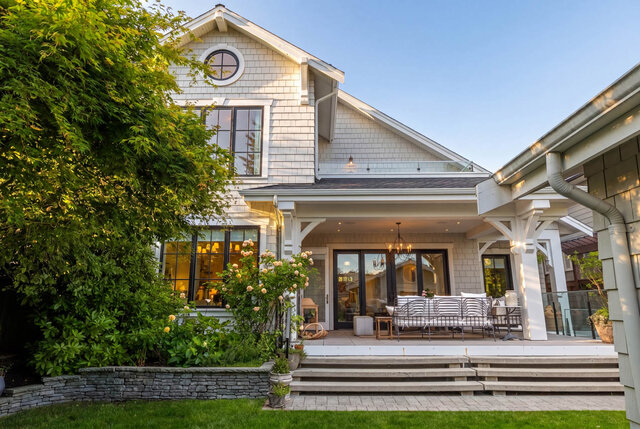 A bright exterior shot of a modern house with large windows, covered porch, and lush landscaping - 1248 Kings Avenue, West Vancouver