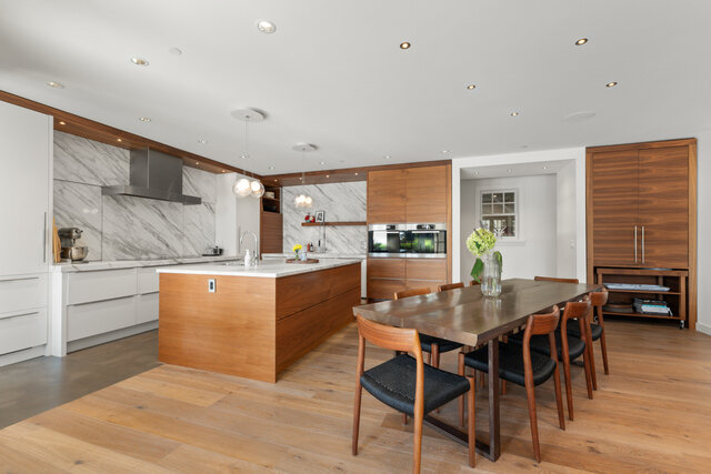 The dining area has a wooden table with chairs, a kitchen with marble backsplash, wooden cabinets, stainless appliances, and 