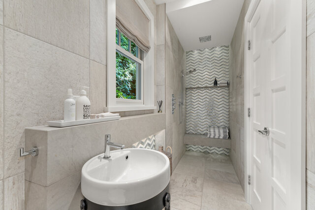 This is a bathroom featuring a sink, a window, a shower area with a bench, and tiled walls. - 2940 Mathers Avenue, West Vancouver