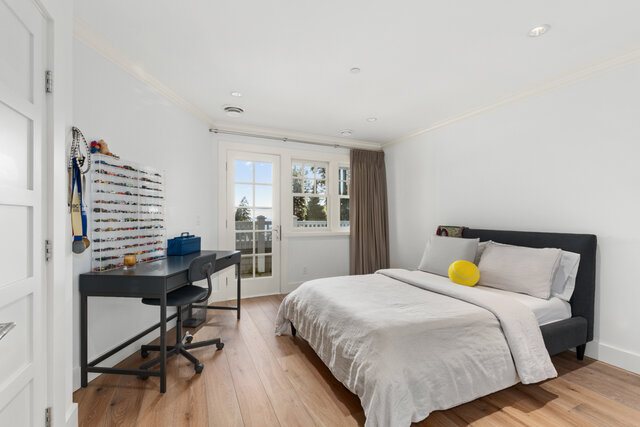 This is a bedroom with a bed, desk, large windows, and hardwood floors. - 2940 Mathers Avenue, West Vancouver