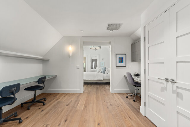 The den has two glass-topped desks with office chairs, hardwood floors, and a sloped ceiling. - 2940 Mathers Avenue, West Vancouver