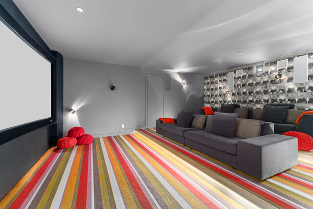 The lounge features a large projector screen, gray sofas, red cushions, a striped rug, and a mirrored wall. - 2940 Mathers Avenue, West Vancouver