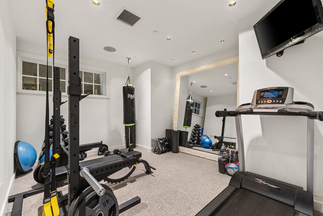 The gym contains a treadmill, weight bench, punching bag, dumbbells, and a stability ball. - 2940 Mathers Avenue, West Vancouver
