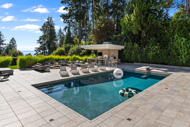The pool area features a swimming pool, lounge chairs, an outdoor kitchen, and pool floats. - 2940 Mathers Avenue, West Vancouver
