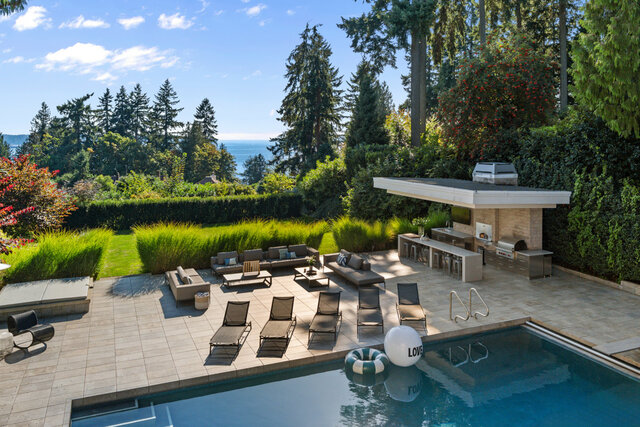 The pool area features lounge chairs, an outdoor kitchen, and a swimming pool with an inflatable float. - 2940 Mathers Avenue, West Vancouver