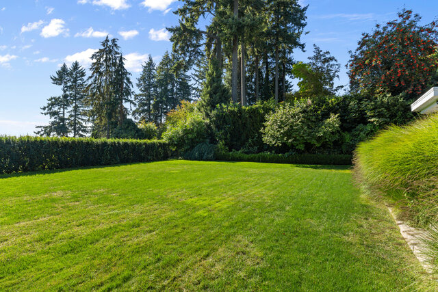 The view shows a large, well-maintained lawn with mature trees and hedges in the background. - 2940 Mathers Avenue, West Vancouver