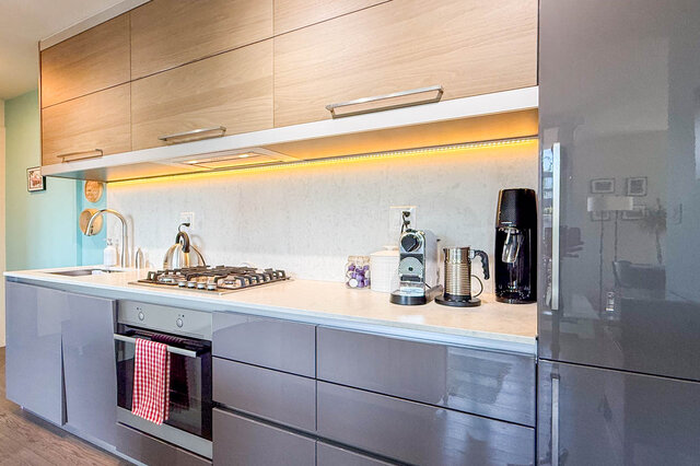 Modern kitchen with sleek gray cabinets and warm under-cabinet lighting. - 505-189 Keefer Street, Vancouver Downtown