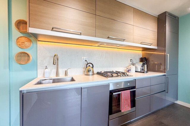 Modern kitchen with light wood upper cabinets and under-cabinet LED lighting. - 505-189 Keefer Street, Vancouver Downtown