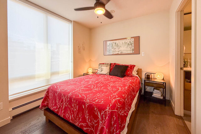 Cozy bedroom with red floral bedspread and hardwood floors. - 505-189 Keefer Street, Vancouver Downtown