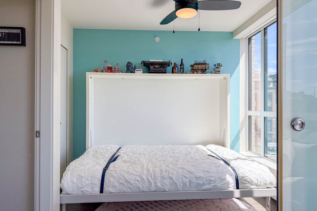 Bedroom with turquoise accent wall and city view through large window. - 505-189 Keefer Street, Vancouver Downtown