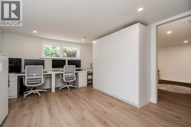 A den with two office desks, computer monitors, office chairs, a large storage cabinet, and a window. - 2784 Crescentview Drive, North Vancouver