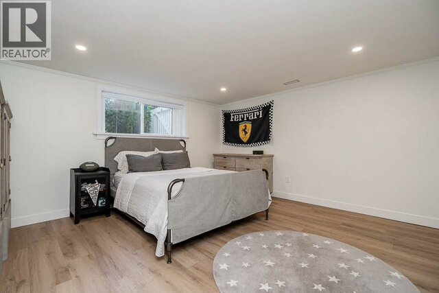 This is a bedroom with a bed, a small window, a round rug, and a dresser. - 2784 Crescentview Drive, North Vancouver