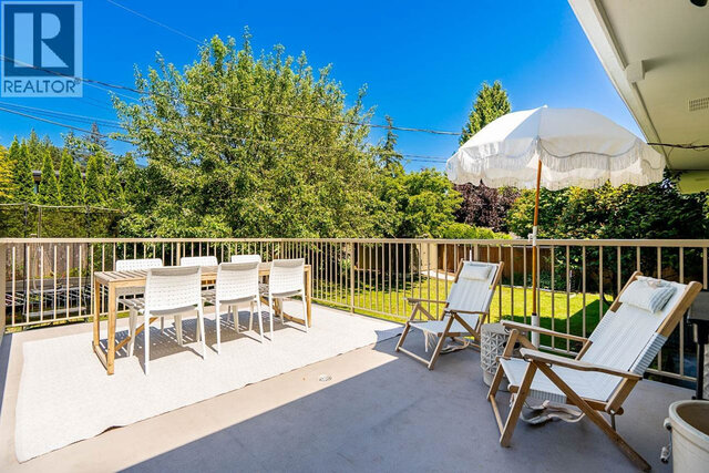 The balcony features a dining table with chairs, lounge chairs, an umbrella, and a rug on the floor. - 2784 Crescentview Drive, North Vancouver