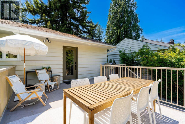 The balcony has a wooden dining table, white chairs, an umbrella, and a railing. - 2784 Crescentview Drive, North Vancouver