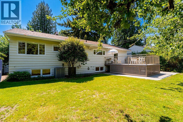 The building exterior shows a single-story house with a deck, outdoor seating, lawn, and surrounding trees. - 2784 Crescentview Drive, North Vancouver