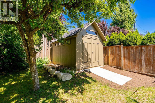 The building exterior shows a shed with a gabled roof, wooden fence, concrete pathway, and rock border. - 2784 Crescentview Drive, North Vancouver