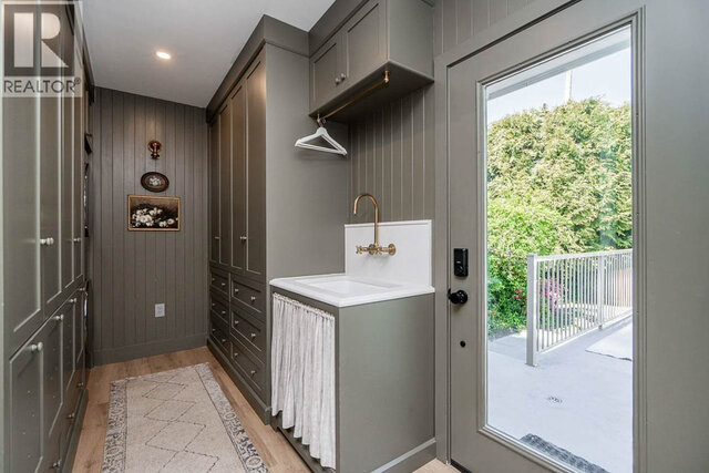 The laundry room features a utility sink, storage cabinets, a hanging rod, and an area rug on the floor. - 2784 Crescentview Drive, North Vancouver