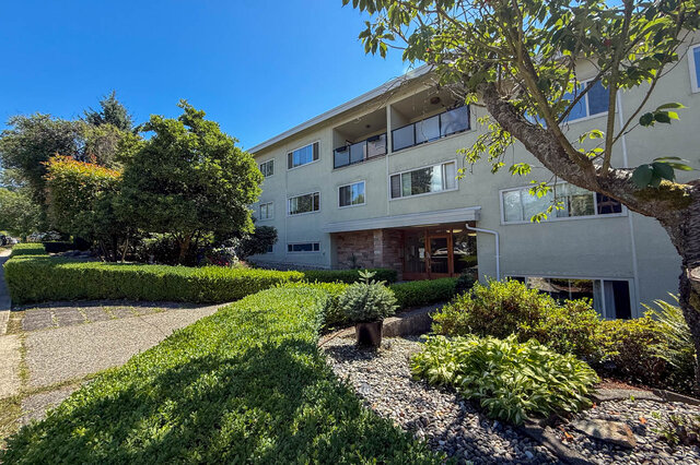 The building exterior shows a multi-story building with balconies, hedges, a tree, and an entrance. - 102-461 16th West street, North Vancouver