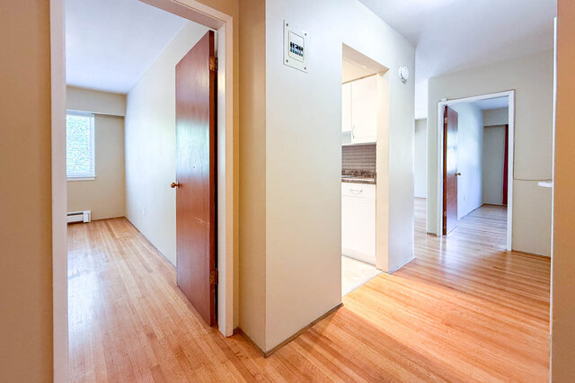 The hallway has hardwood floors, a window in an adjacent room, and wooden doors. - 102-461 16th West street, North Vancouver
