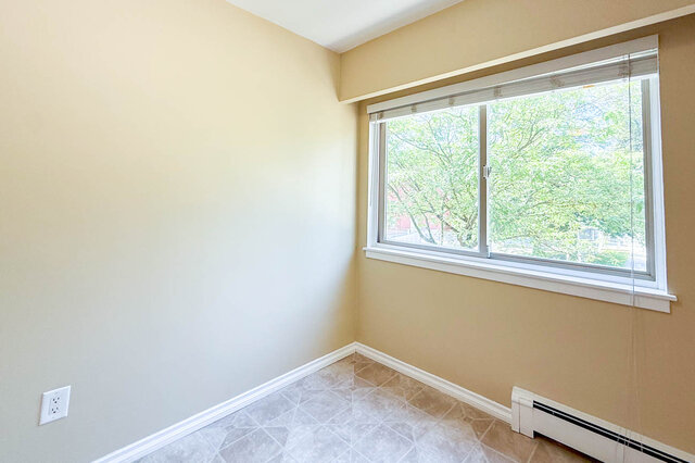 This is a bedroom with a window, tile flooring, and a baseboard heater. - 102-461 16th West street, North Vancouver