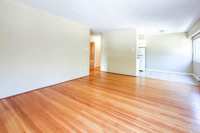 The living room has hardwood floors and a small window, with an open layout and a view into the kitchen area.