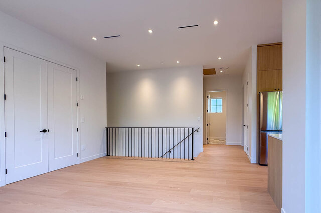Open living area with light hardwood floors and black metal railing. - 3038 Vine Street, Vancouver West Side