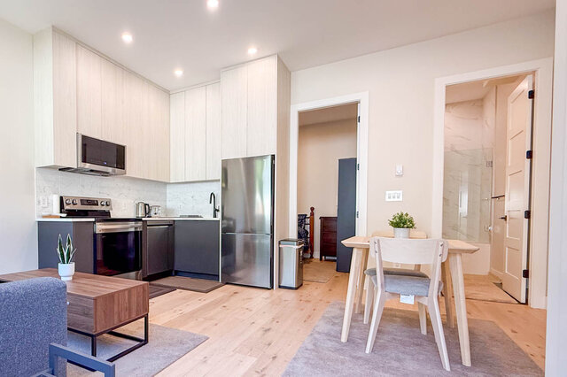 Open kitchen with stainless steel appliances, light wood cabinetry, and hardwood floors. - Suite-1384 Hope Road, North Vancouver
