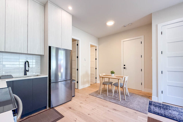 Kitchen and dining area with stainless steel fridge, white cabinetry, and light hardwood floors. - Suite-1384 Hope Road, North Vancouver