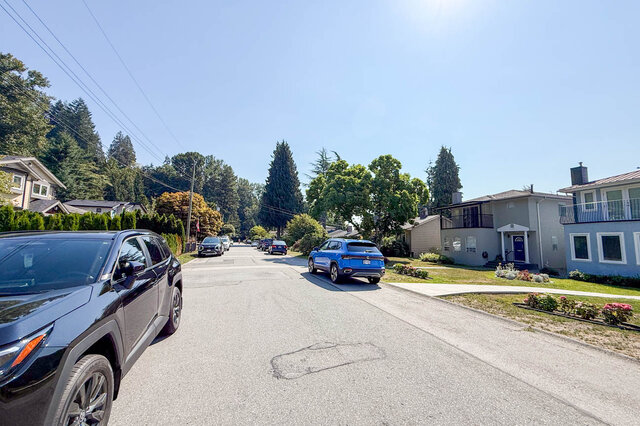 Quiet tree-lined residential street with parked cars and single-story homes under a clear blue sky. - Suite-1384 Hope Road, North Vancouver