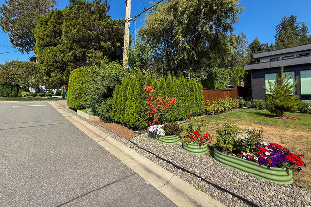 Lush front garden with manicured hedges and colorful flower planters along a quiet street. - Suite-1384 Hope Road, North Vancouver