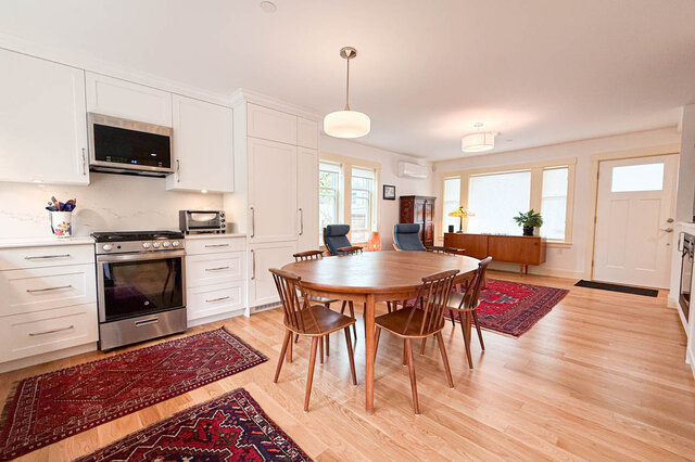Bright kitchen and dining area with white cabinetry, stainless steel range, and light hardwood floors. - 3752 West 23rd Avenue, Vancouver West Side