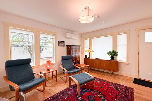 Furnished living room with hardwood floors, blue lounge chairs, and a red patterned rug. - 3752 West 23rd Avenue, Vancouver West Side
