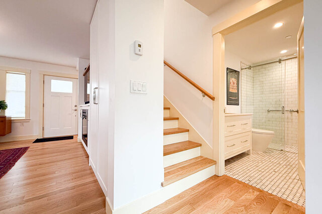 Entry hallway with light hardwood floors and a wood-tread staircase beside a white-tiled bathroom. - 3752 West 23rd Avenue, Vancouver West Side