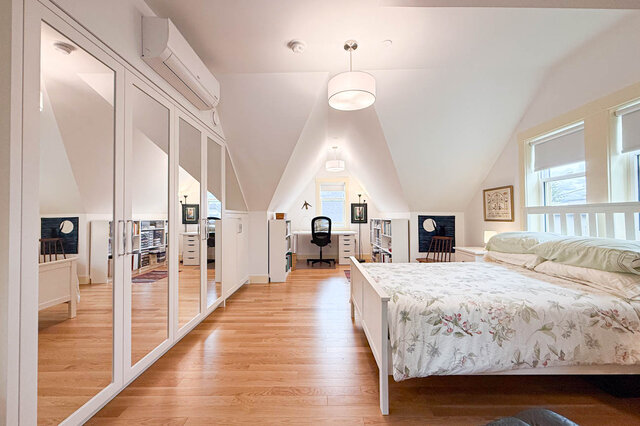 Bright bedroom with hardwood floors, mirrored closet doors, and a floral bed under vaulted ceilings. - 3752 West 23rd Avenue, Vancouver West Side