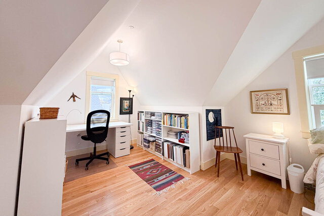 Furnished attic study with sloped ceilings, hardwood floors, white desk, and built-in bookshelves. - 3752 West 23rd Avenue, Vancouver West Side